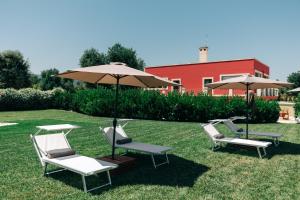 a group of chairs and umbrellas on the grass at Appartamento Sea - Tenuta Fascianello in Fasano