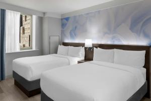 two beds in a hotel room with white sheets at Four Points by Sheraton New York Downtown in New York +90 photos