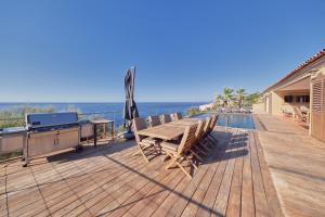 a wooden deck with a table and chairs and the ocean at Cala Di Mare Villa in Calvi +48 photos