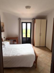 a bedroom with a white bed and a sliding glass door at Agriturismo Terra Del Mare in Fossalòn
