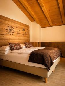 a bedroom with a large bed with a wooden wall at B&B Te Nìf in Predazzo