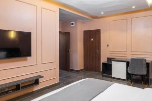 a room with a bed and a desk and a television at BON Hotel Emporium in Ughelli +26 photos
