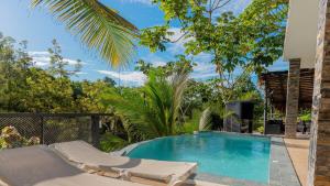 a swimming pool with two lounge chairs and a palm tree at Villa Palacio Verde Las terrenas in Las Terrenas