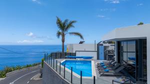 a house with a swimming pool next to the ocean at Villa Stella by LovelyStay in Arco da Calheta