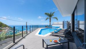 a balcony with a pool and a view of the ocean at Villa Stella by LovelyStay in Arco da Calheta