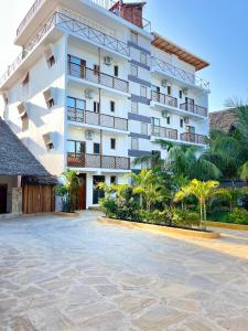 a large white building with palm trees in front of it at Maji Pearl Hotel & Spa in Nungwi