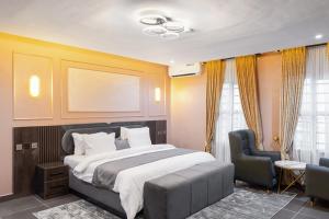a bedroom with a large bed and a chair at BON Hotel Emporium in Ughelli