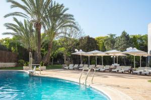 ein Schwimmbad mit weißen Liegestühlen und Sonnenschirmen in der Unterkunft Checkin Valencia Ciscar in Picanya