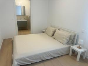 a bed with white sheets and pillows in a room at Appartamento Stella - 15' walk to Abano Terme centre in Abano Terme