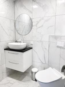 a white bathroom with a sink and a mirror at Mis apartamentai in Mažeikiai
