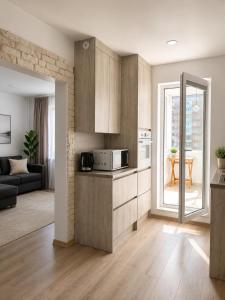 a kitchen with wooden cabinets and a living room at Mis apartamentai in Mažeikiai