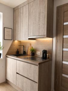 a kitchen with wooden cabinets and a sink at Mis apartamentai in Mažeikiai +2 photos