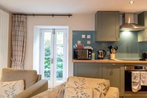 a living room with a couch and a kitchen at Newton Cottage South in Inveraray
