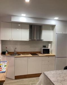 a kitchen with white cabinets and a sink and a microwave at Apartamento Hércules in Ceuta