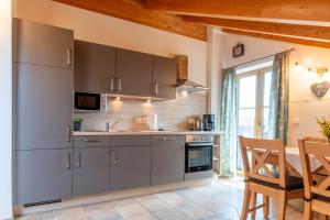 a kitchen with gray cabinets and a table and a dining room at Kramerhof - Ferienwohnung Wallberg in Aufhofen