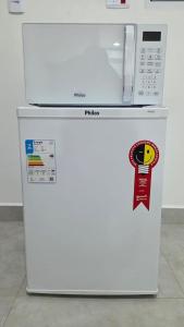 a white refrigerator with a microwave on top of it at Suítes confortáveis próximo ao Sesc in Bertioga