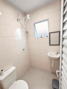 a bathroom with a toilet and a sink at Suítes confortáveis próximo ao Sesc in Bertioga +17 photos