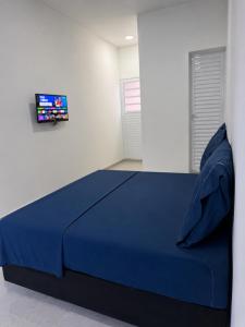 a bedroom with a blue bed with a tv on the wall at Suítes confortáveis próximo ao Sesc in Bertioga