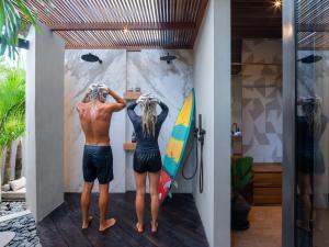 two people standing in a room with a surfboard at Award-Winning 3BR Villa 25m Pool Villa FEH in Kerobokan +43 photos