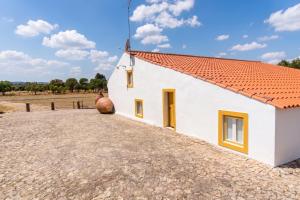a white house with a red roof and a field at Kochab Alentejo in Crato