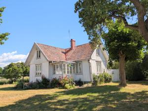 a white house with a tree in the yard at Bond-Gården in Fågelmara
