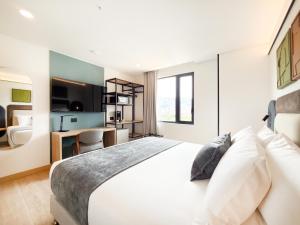a bedroom with a white bed and a desk at Blues Suites Laureles in Medellín