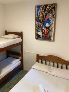 a room with two bunk beds and a painting on the wall at Papagaio Hostel & Pousada in Morro de São Paulo +82 photos