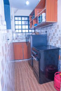 a kitchen with a black stove and wooden cabinets at Micasa Homes BNB GF in Limuru