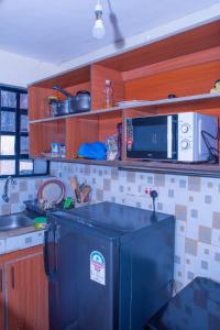a kitchen with a microwave and a refrigerator at Micasa Homes BNB GF in Limuru