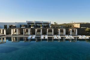 a group of chairs sitting next to a swimming pool at Oroséa Paros - Adults Only, Autograph Collection in Naousa
