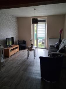 a living room with a couch and a tv at Gîte des Vieilles Forges in Fromelennes