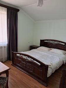 a bedroom with a large wooden bed with white sheets at Green Dilijan B&B in Dilijan