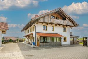 a large white house with a wooden roof at Kramerhof - Ferienwohnung Wallberg in Aufhofen