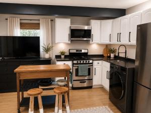 a kitchen with white cabinets and a table with stools at Cozy Private Studio in Des Moines