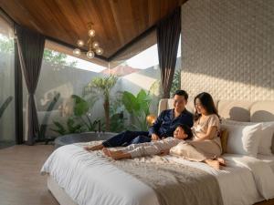 a family sitting on a bed in a living room at Award-Winning 3BR Villa 25m Pool Villa FEH in Kerobokan