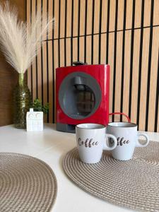 two coffee cups on a table next to a microwave at Apartmán Větrná s klimatizací a terasou in Zlín