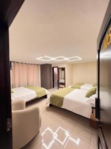 a hotel room with two beds and a chair at Casa Herrerías Hotel & Confort in Cuenca