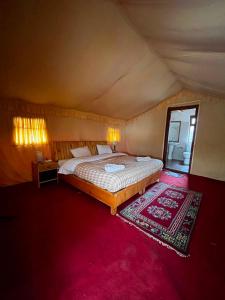 a bedroom with a large bed and a red carpet at Mystique Meadows Swiss Cottages in Nubra