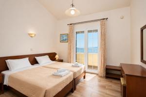 a bedroom with two beds and a large window at Ioannas House in Nisaki +19 photos