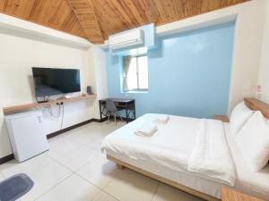 a bedroom with a white bed and a tv at 好馨情民宿 in Nangan