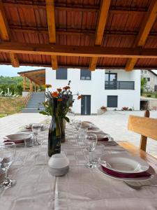 a table with plates and glasses and a vase with flowers at Plitvice House Lina in Rakovica