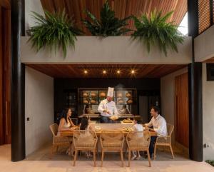 a group of people sitting around a table in a kitchen at Award-Winning 3BR Villa 25m Pool Villa FEH in Kerobokan