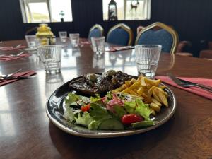 Ein Teller mit Essen auf einem Tisch, bestehend aus Salat und Pommes frites. in der Unterkunft Studlagil INN Hostel in Skjöldólfsstaðir