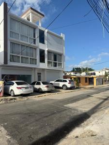 a white building with cars parked in front of it at Apartamento Carmen céntrico in Santa Bárbara de Samaná
