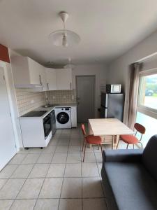 a kitchen with white appliances and a table and chairs at Le Cocon de Sévérac I Clim & cour intérieure in Sévérac d' Aveyron
