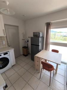 a kitchen with a refrigerator and a table and a stove at Le Cocon de Sévérac I Clim & cour intérieure in Sévérac d' Aveyron +3 photos