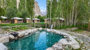 a pool of water in a yard with trees at Mystique Meadows Swiss Cottages in Nubra