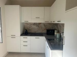 a white kitchen with white cabinets and a sink at San Leo Apartment in Stia