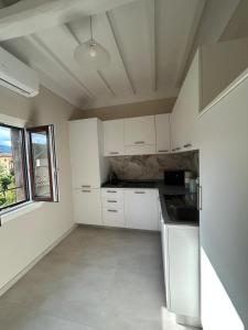 a kitchen with white cabinets and a large window at San Leo Apartment in Stia