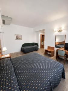 a bedroom with a bed and a couch and a mirror at Hotel Italia in Ravenna